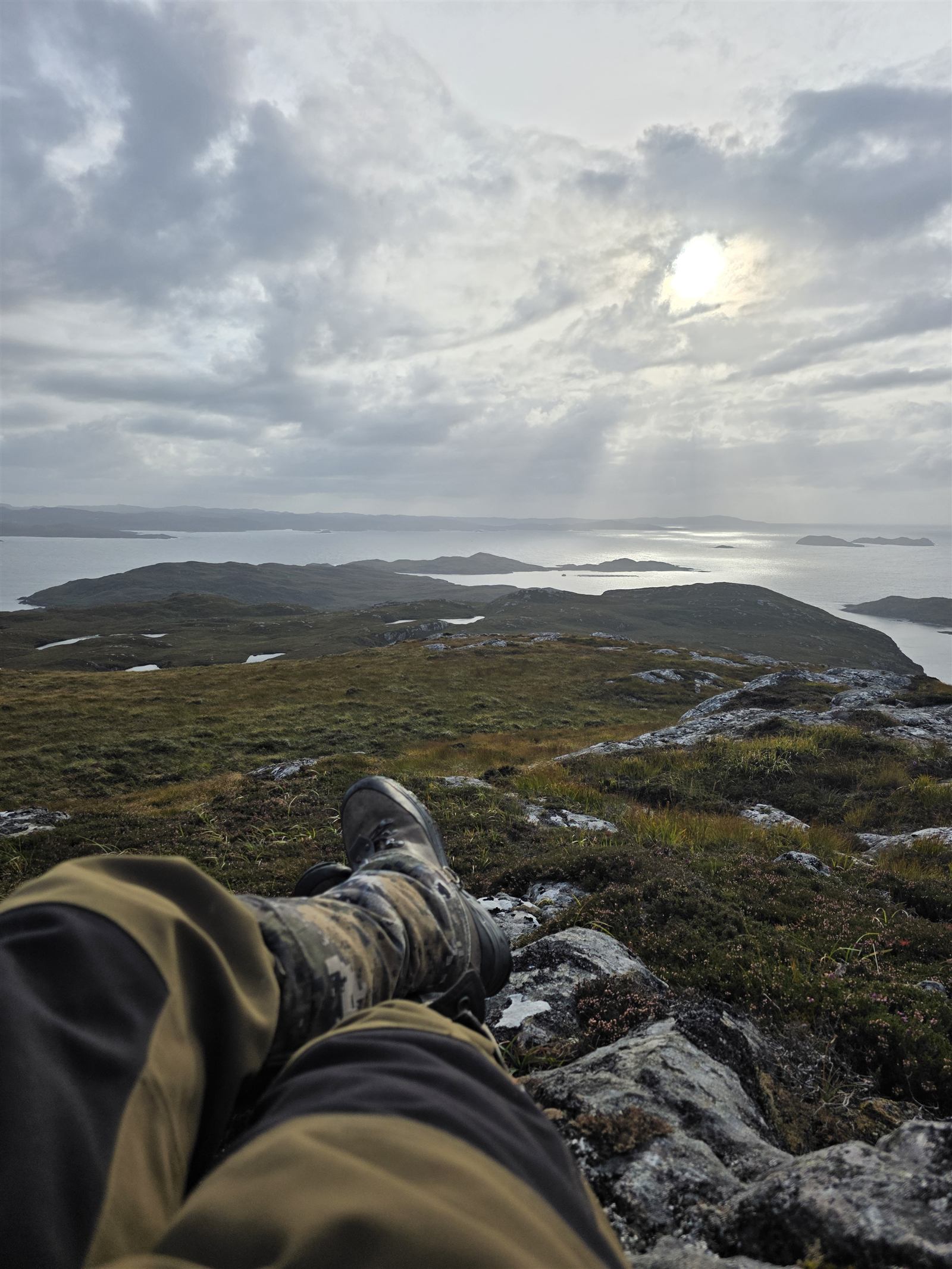 Glassing the coast from the hill, boots and waterproofs in shot